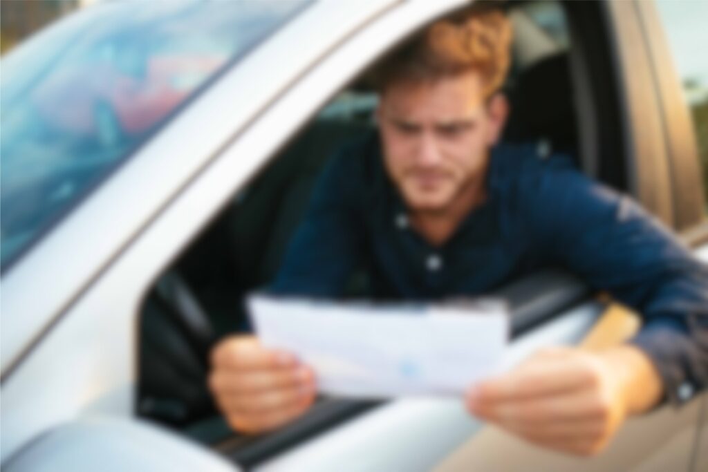 Homem lendo documento dentro do carro.