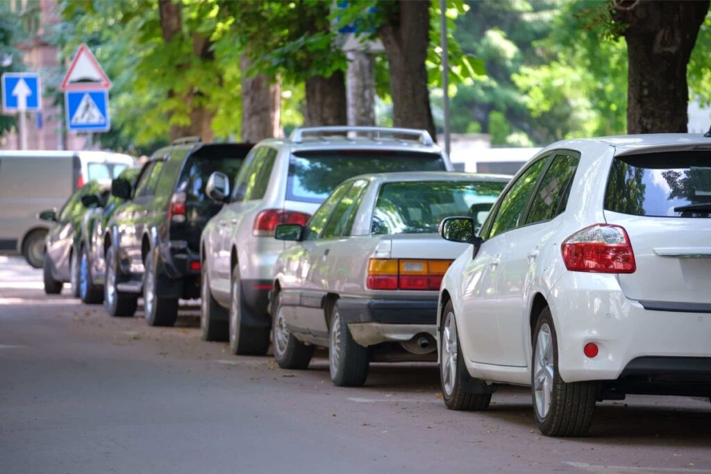 Carros estacionados ao lado da rua arborizada.